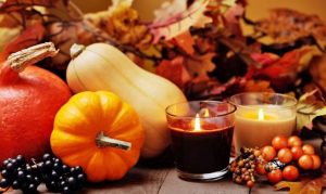 Die schönsten Herbst-Dekorationen, Bild-Motiv: verschiedene Kürbisse, buntes Herbstlaub und zwei Kerzen im Glas