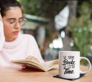 Junge lesende Frau mit weißer Keramiktasse Tasse für Buch-Fans mit Aufdruck: „So many books, so little time.“