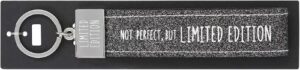Schlüsselanhänger aus grauem Filzband, Metallklemme und Schlüsselring. Aufdruck auf dem Band: NOT PERFECT. BUT LIMITED EDITION Gravur auf der Metallklemme: LIMITED EDITION