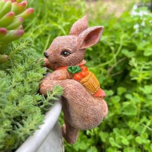 kleiner Osterhase mit orangerotem Umhang klettert in einen Blumenkübel