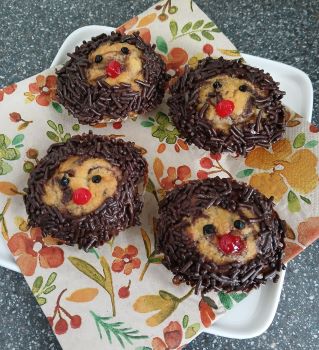 Igel-Muffins: Muffins mit Rand aus Schokostreuseln und schwarzen Augen und roter Nase aus Zuckerglasur