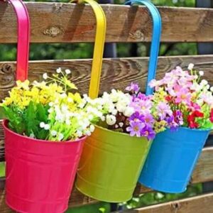 Hängende Blumentöpfe in verschiedenen Farben mit buntenFrühlingsblumen